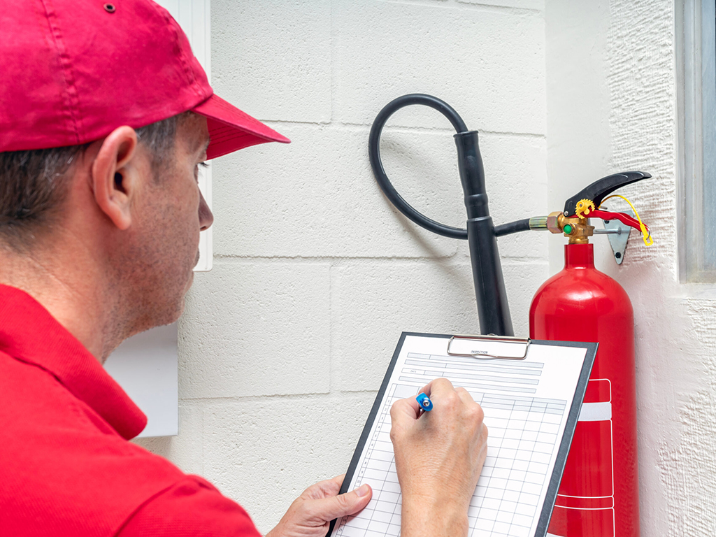 A service technician records data from a fire extinguisher.
